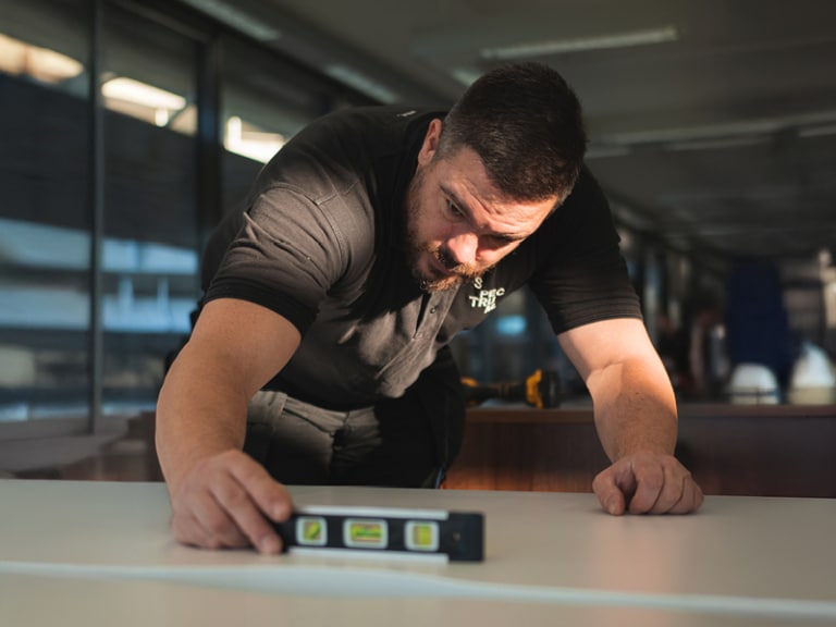 A Spectrum designer uses a levelling device during an office fit out project