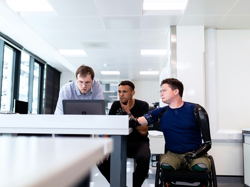 Three colleagues collaborate on an accessible workplace; one colleague requires accessibility considerations themselves