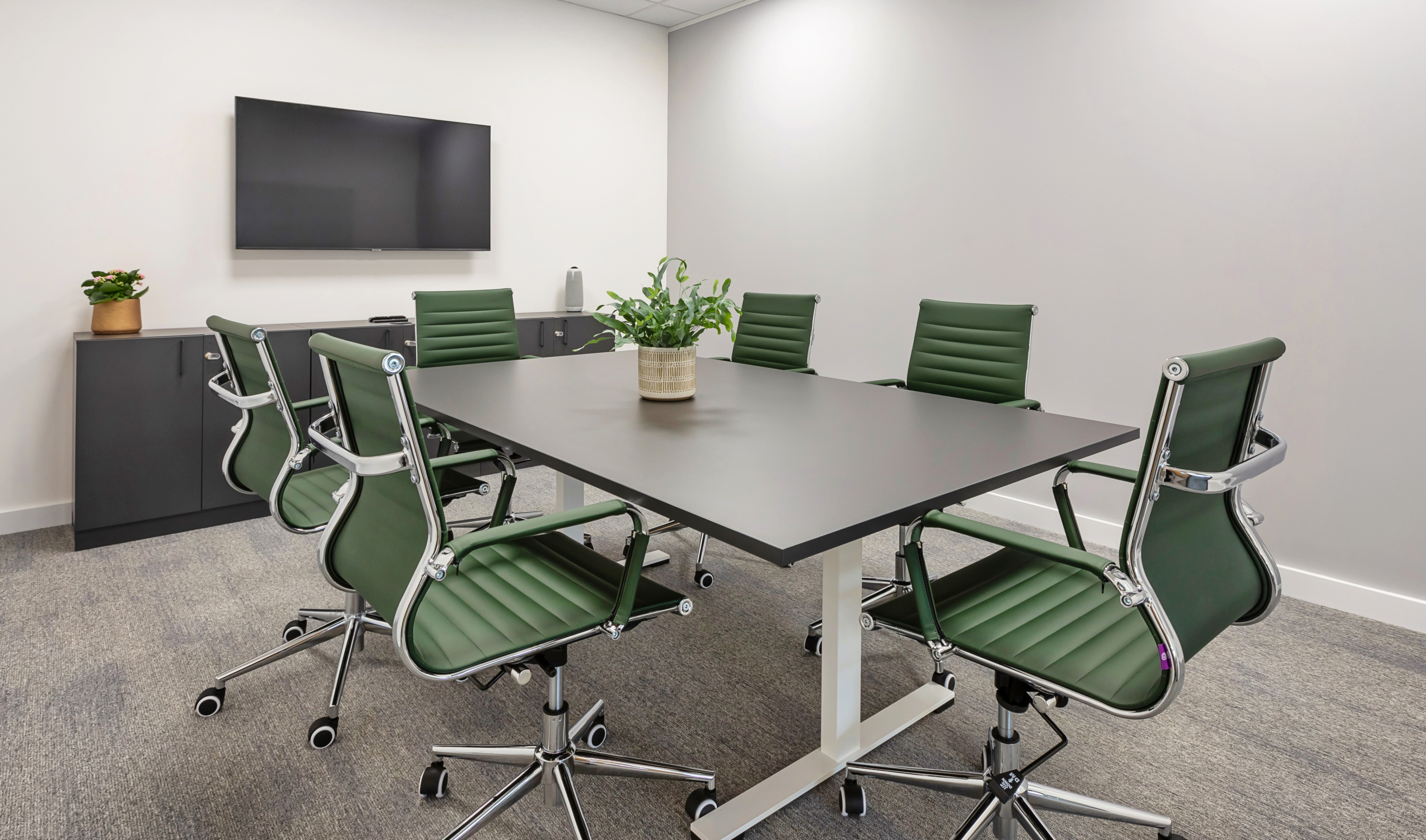 Neutral executive office with green chairs and boardroom table