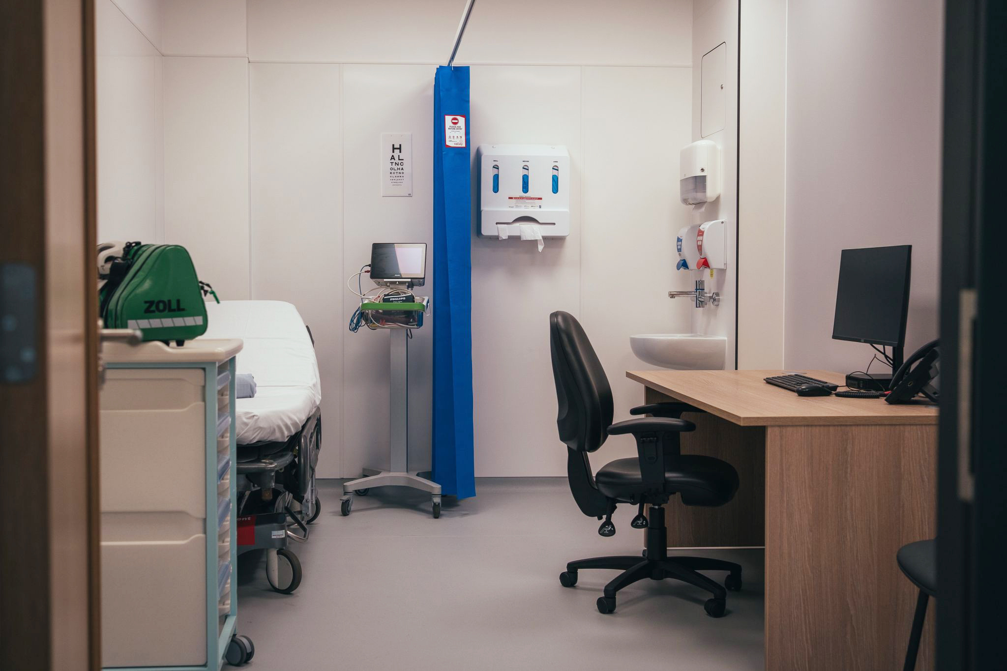 Medical room with patient bed and doctor seating area