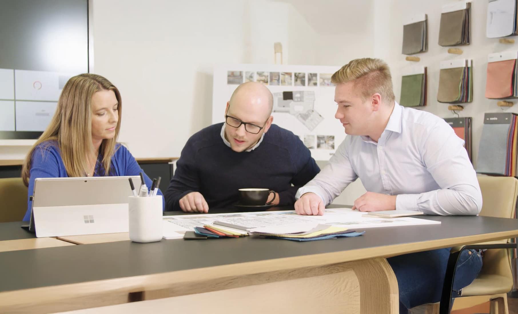 Three colleagues collaborate together over workplace designs