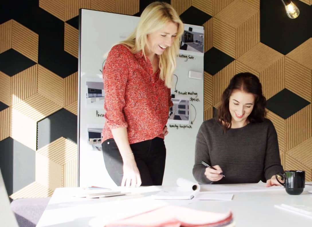 Two colleagues collaborate together over workplace designs