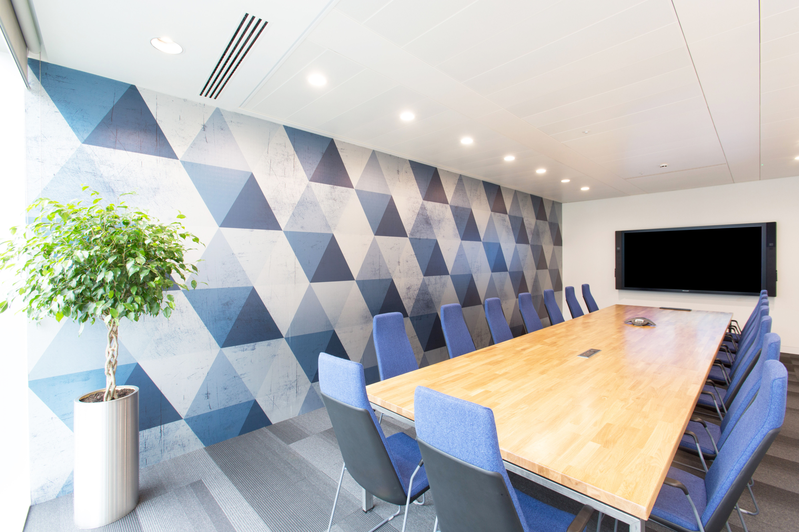 Boardroom meeting room with geometric background and blue chairs