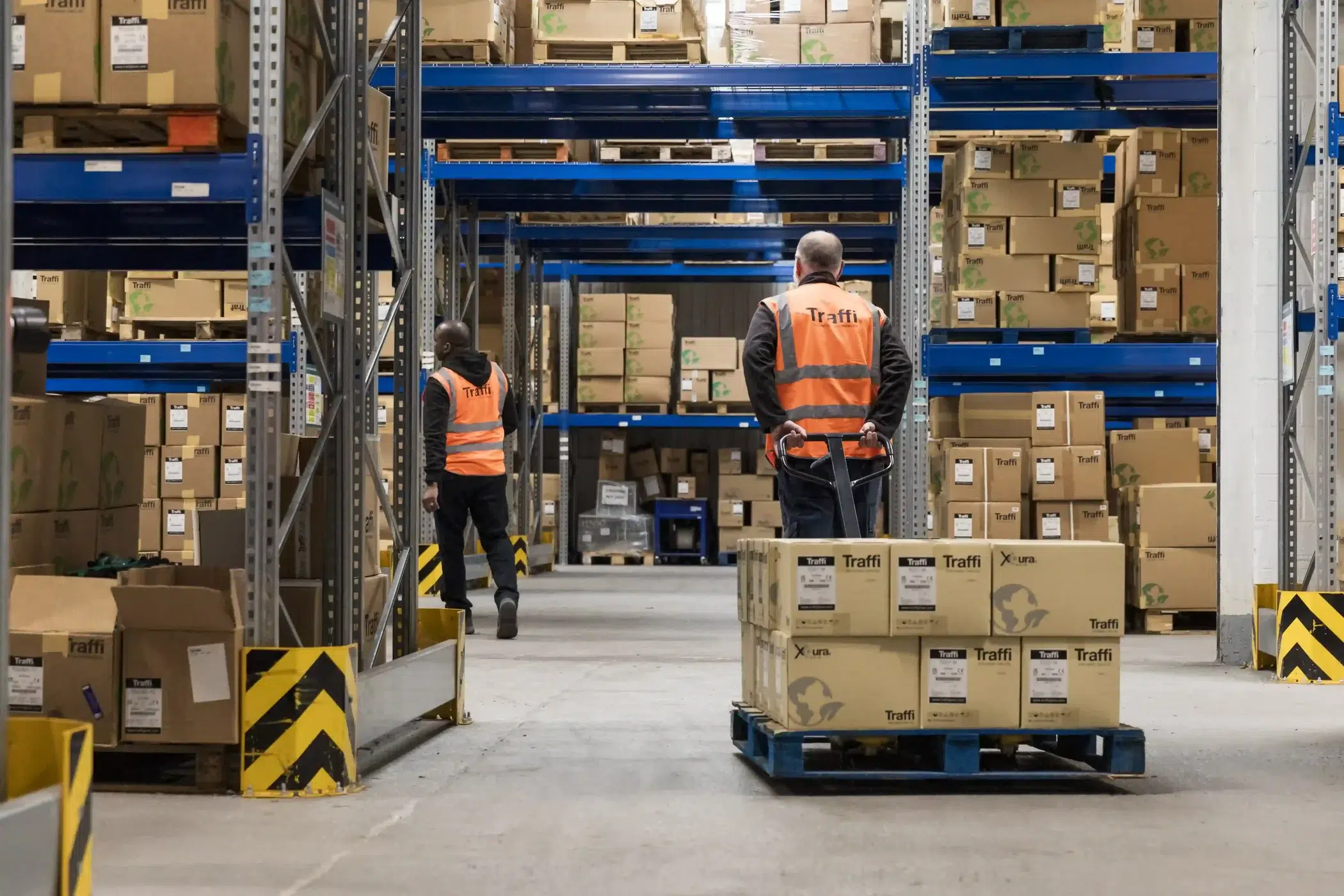 Two men in orange high vis jackets working in warehouse