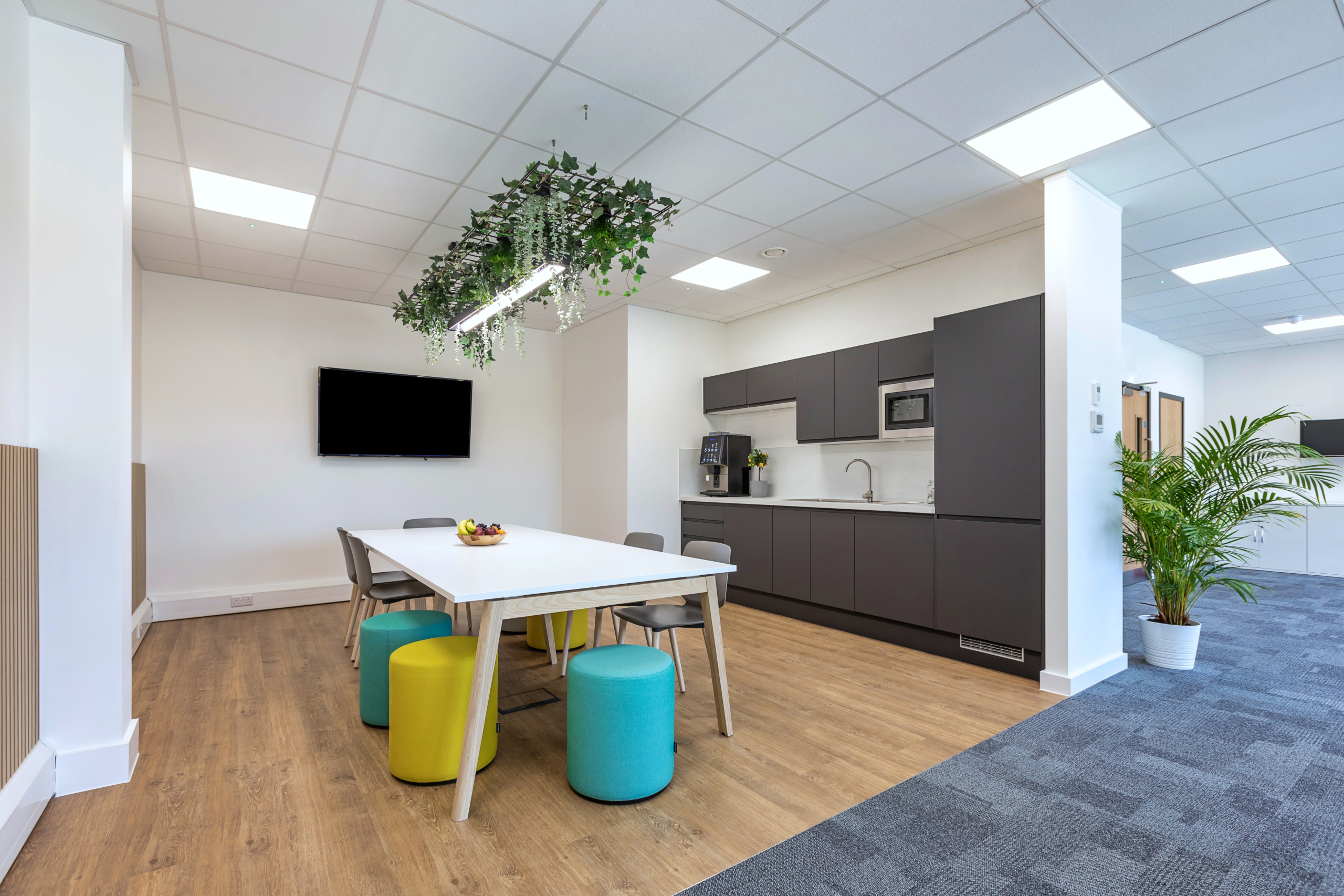 Teapoint seating area with colourful poofs and television with biophilic elements